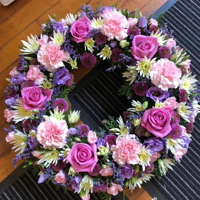 Pink and Purple Memorial Wreath - A stunning wreath of pink and purple flowers, including roses and carnations. A heartfelt tribute for funerals.